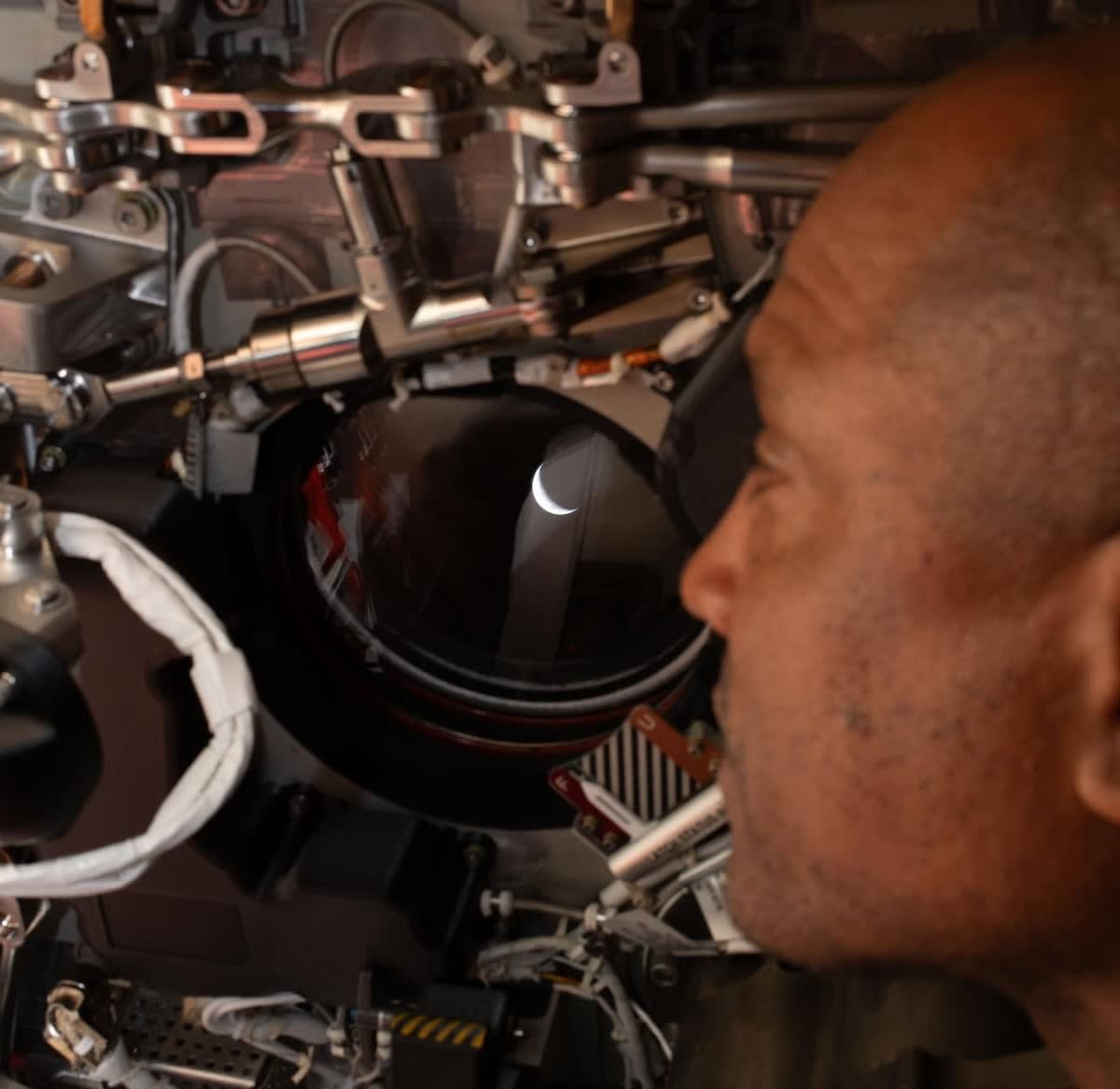 Astronaut Victor Glover views crescent Earth through Orion spacecraft window during lunar mission