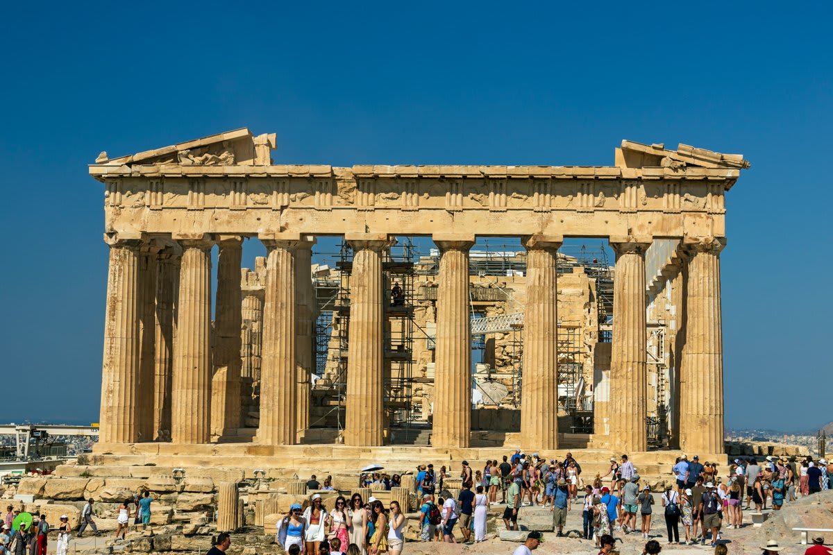 Ancient Parthenon temple with white marble columns standing on curved stone platform in Athens