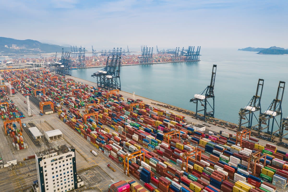 Cargo ship stacked with thousands of colorful shipping containers on the ocean