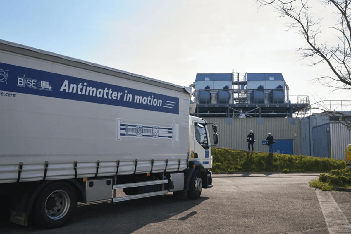 White truck on CERN campus carrying one-ton antimatter transport container with scientific equipment
