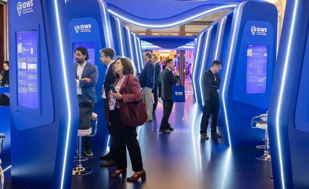 ** Scientists and innovators collaborating at water technology conference with digital displays showing conservation solutions