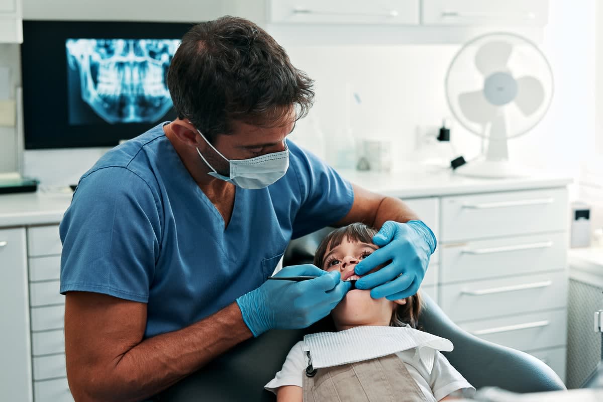 Young child smiling at dentist office showing healthy teeth after pain-free cavity treatment
