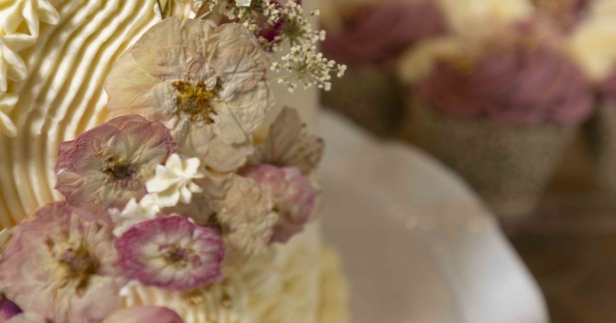 Mia Marshall decorating an elegant multi-tiered wedding cake in her home kitchen