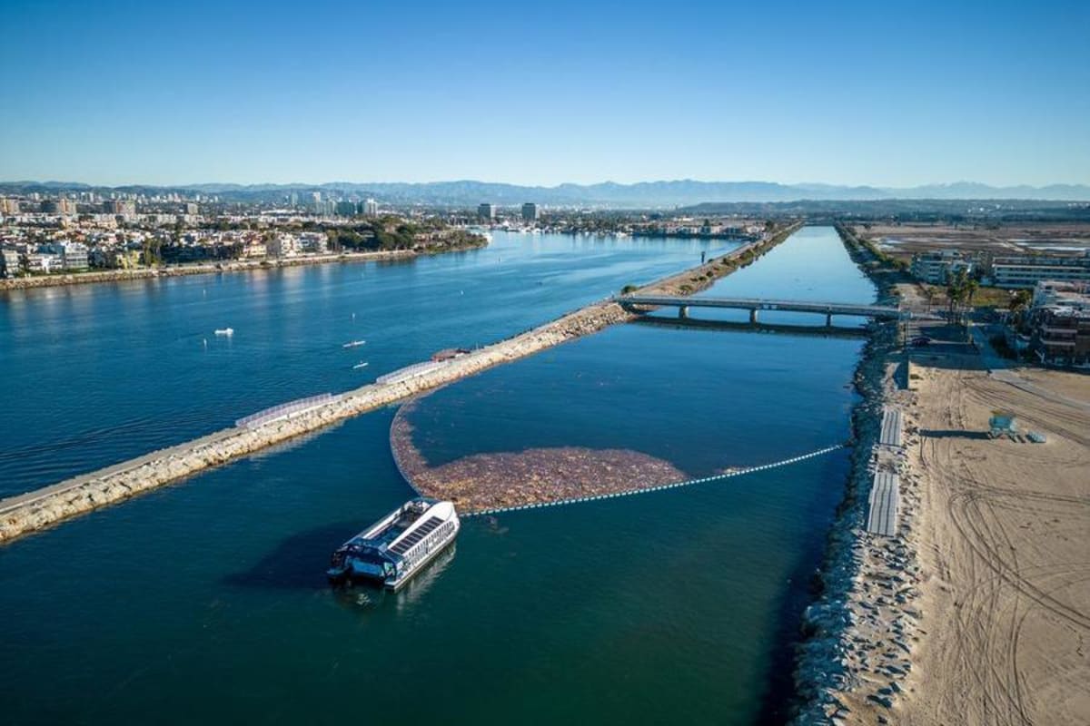Floating trash interceptor device collecting plastic waste in Los Angeles river before Olympics