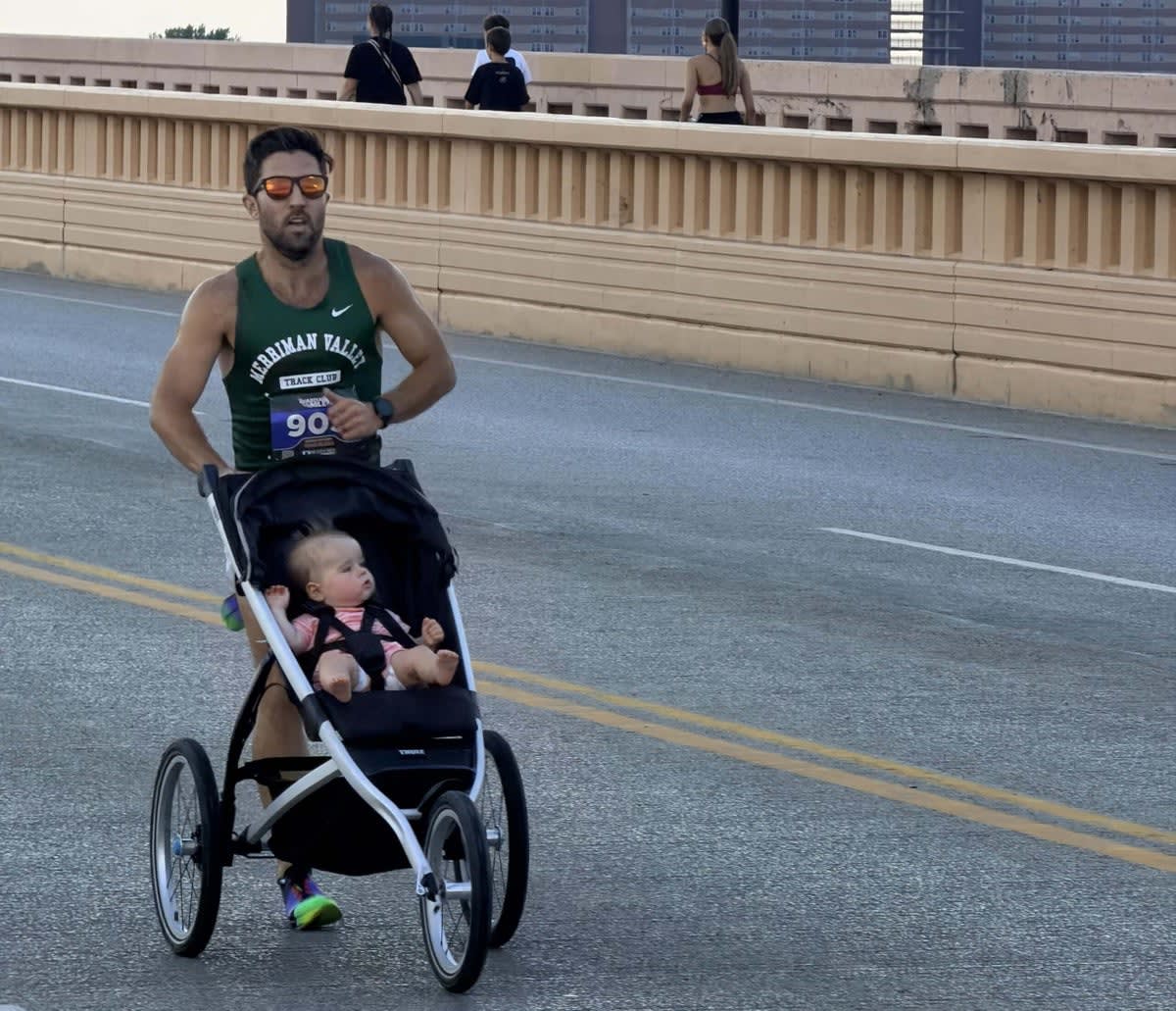 ** Father running with athletic racing stroller pushing young child on track or road