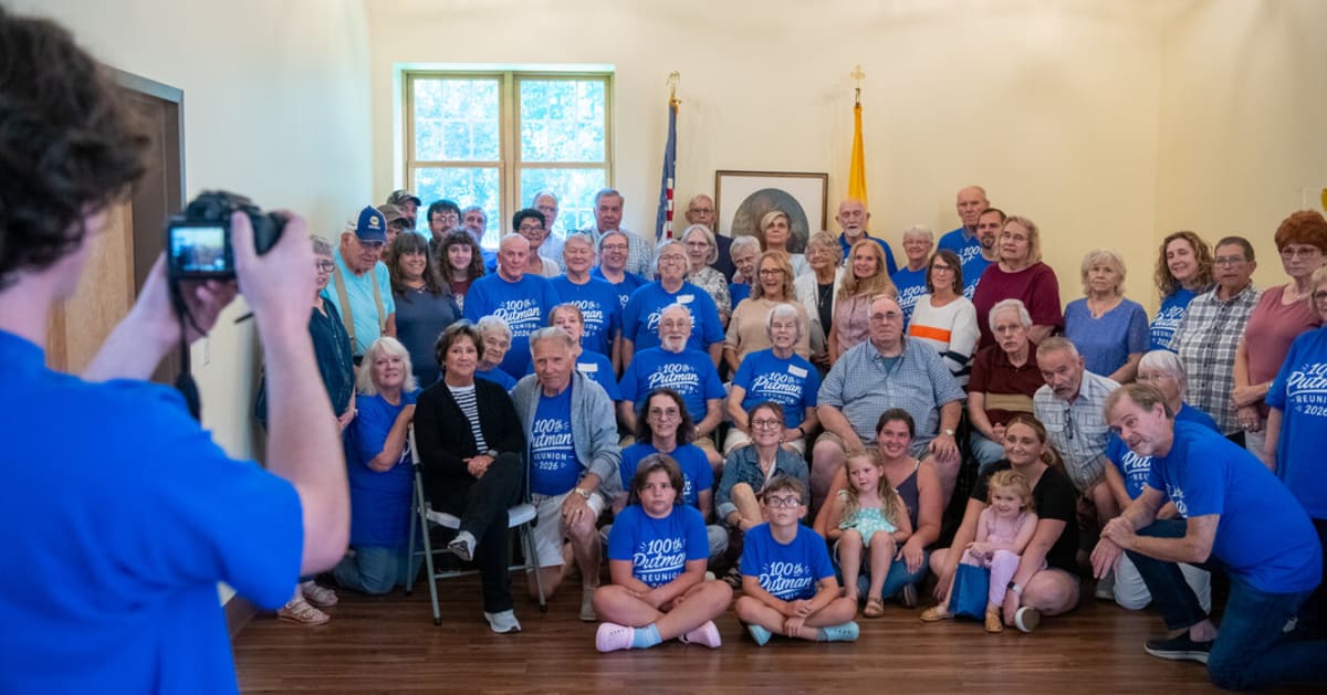 Elderly family members gathered around tables at indoor reunion hall with food and photographs