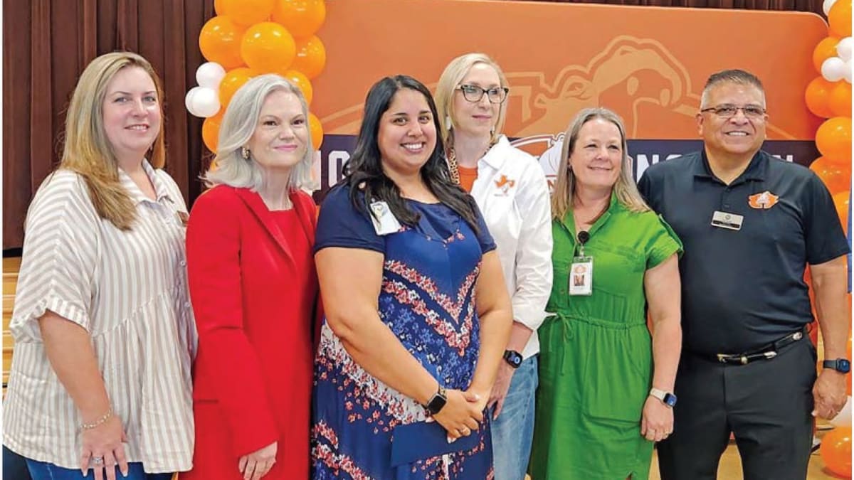 Kindergarten teacher Olivia Joseph holds award certificate surrounded by smiling school board members