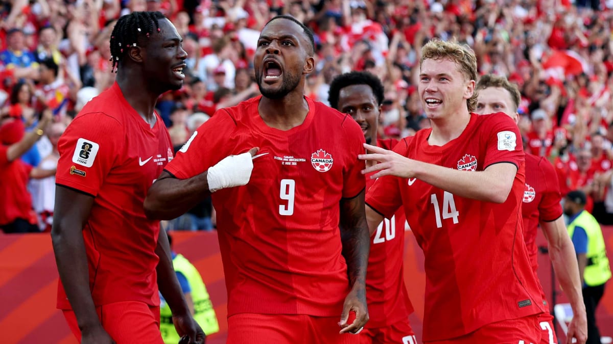 Canadian soccer player Cyle Larin celebrating goal with teammates in red jerseys at Toronto stadium