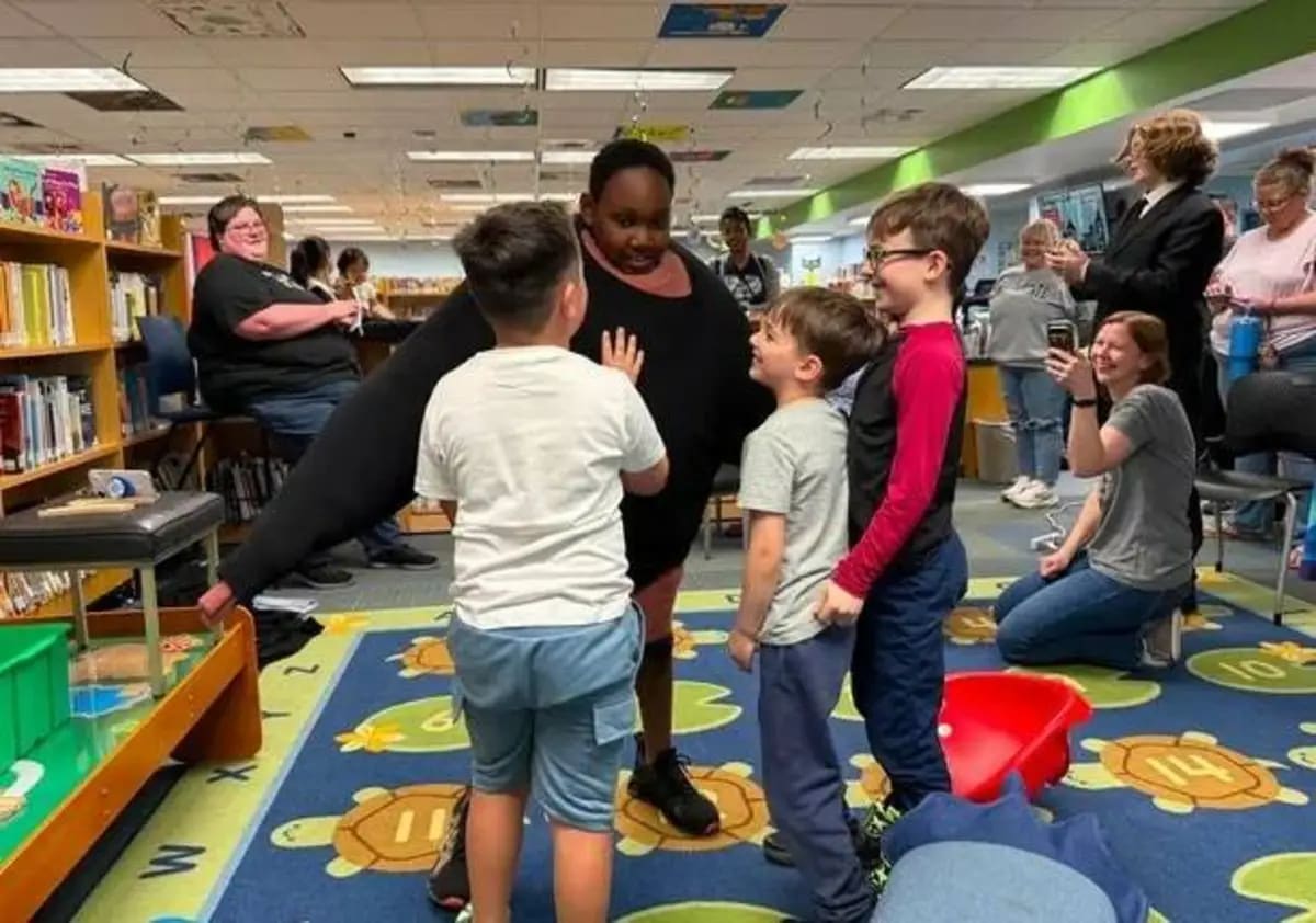 ** Seven-year-old boy wearing dozens of sweaters appearing very puffy while smiling at library
