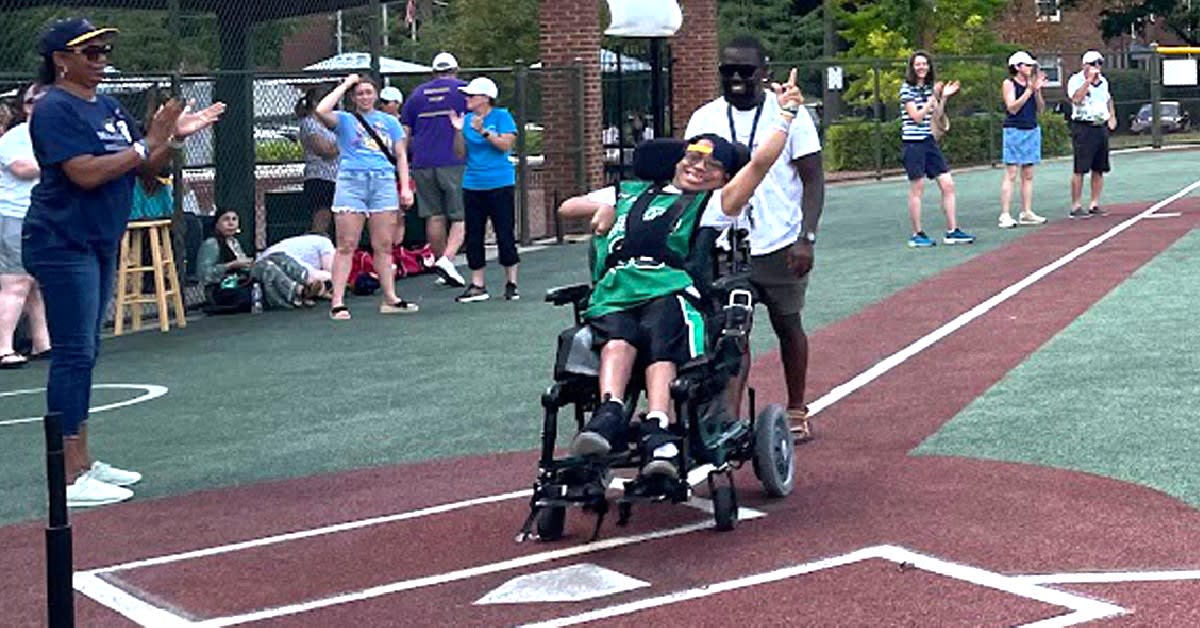 Volunteer Angel helping Miracle League baseball player cross home plate at Alexandria's Kelley Cares Field
