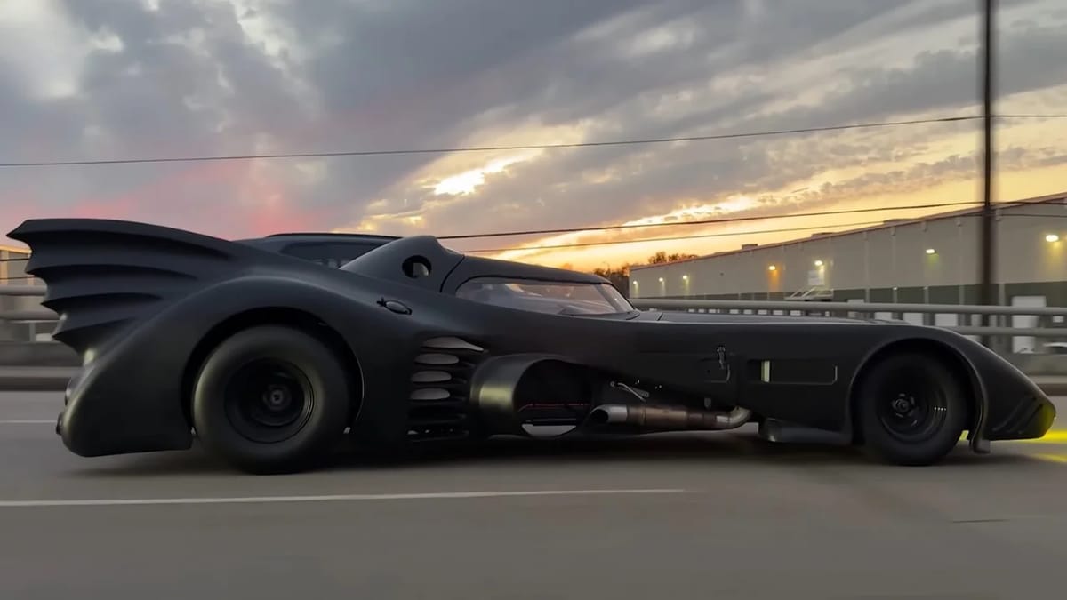 Road-legal Batmobile replica from 1989 film driving on public street with dramatic black bodywork