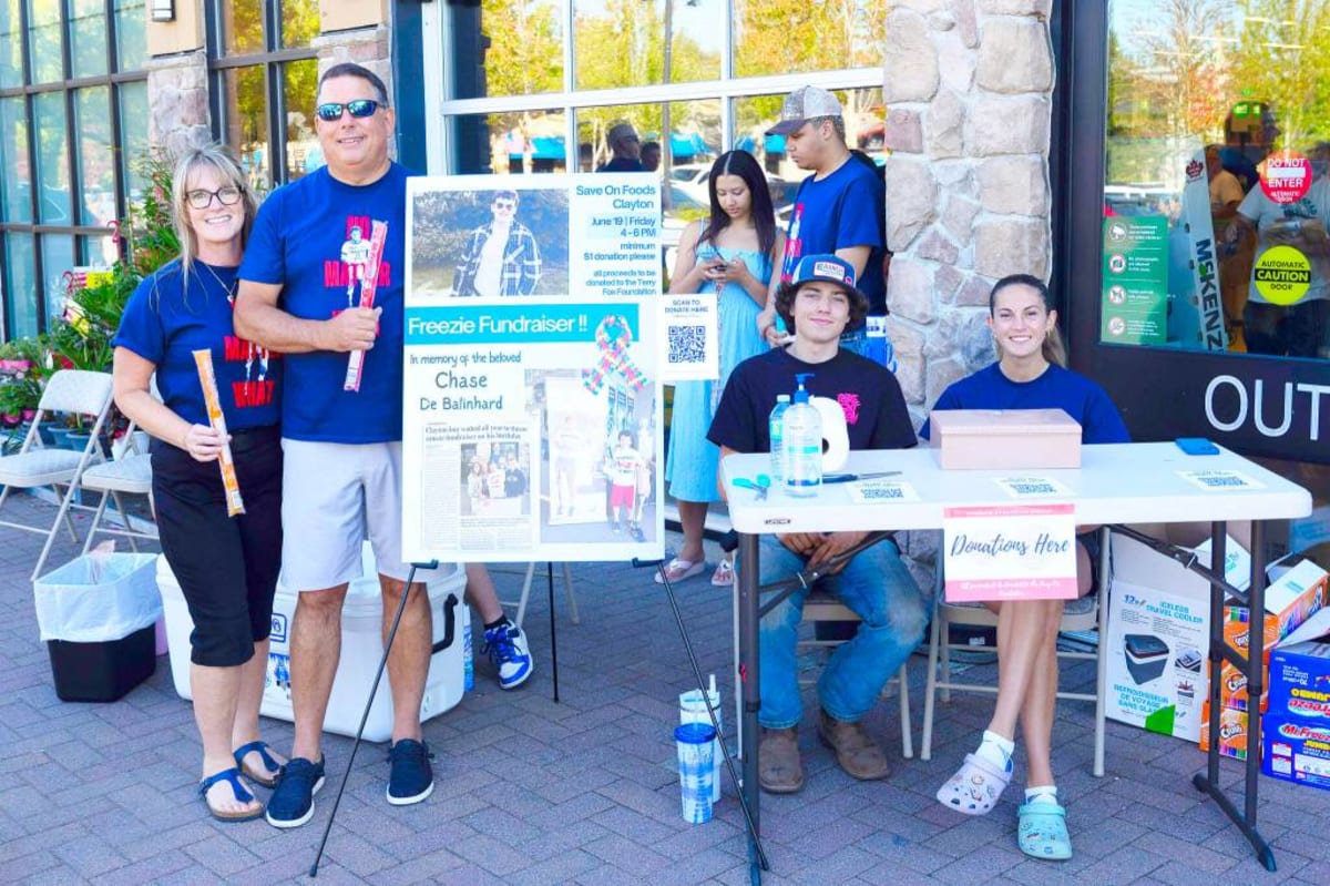 Teens and parents stand outside grocery store holding fundraiser sign for Terry Fox Foundation