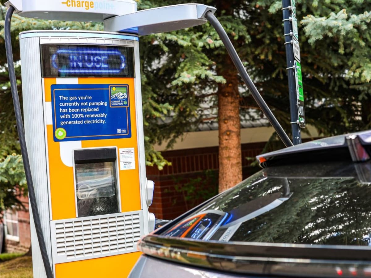 Electric vehicle charging at public charging station in Colorado with mountains in background