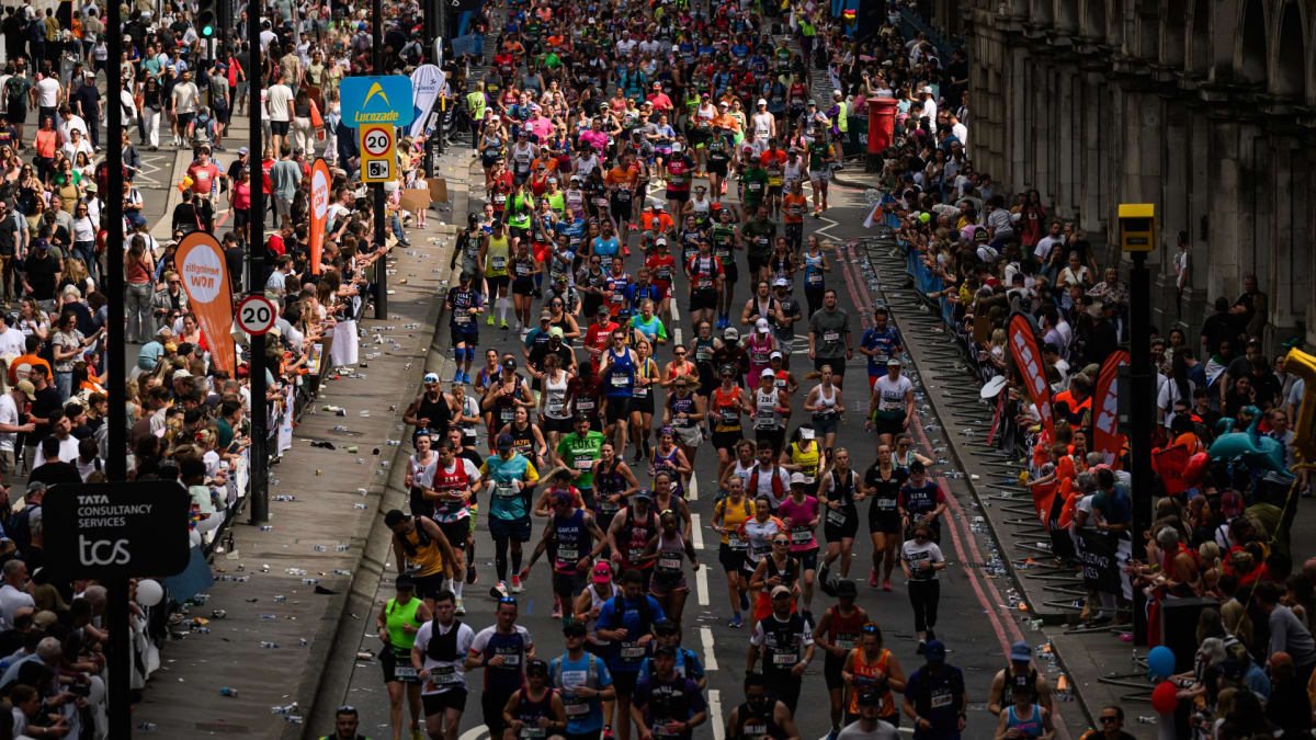 Thousands of marathon runners crossing the starting line at London Marathon with cheering crowds