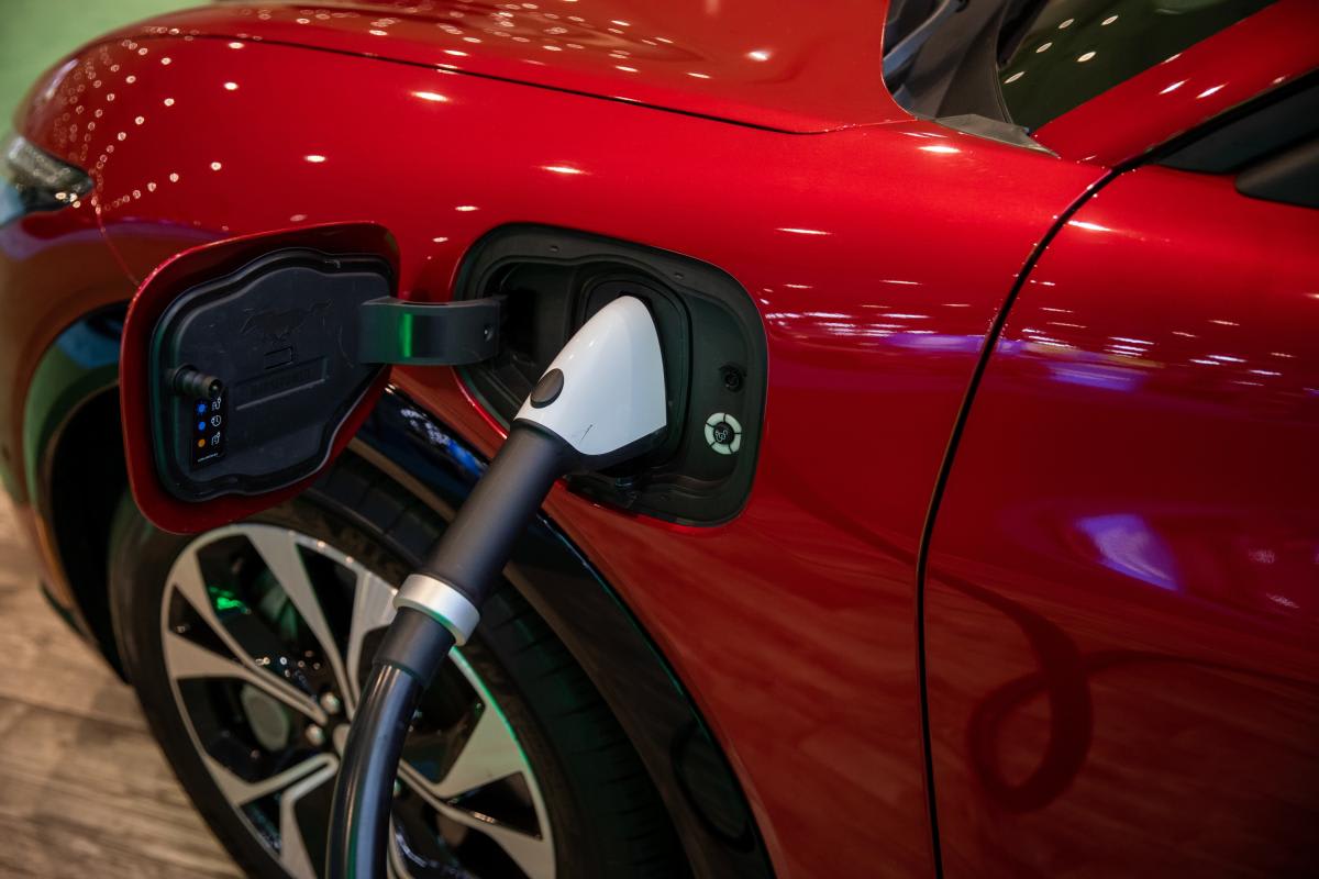 Electric vehicle plugged into modern fast charging station with green indicator lights showing successful connection