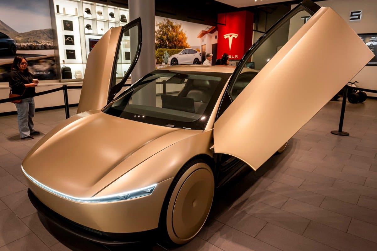 Gold Tesla Cybercab autonomous vehicle with two seats driving on Austin street
