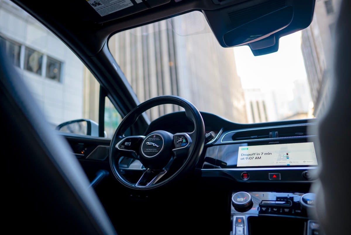 White Waymo self-driving vehicle parked at airport terminal pickup area