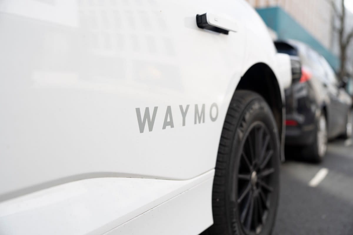 White electric Jaguar I-Pace with Waymo sensors driving on London street