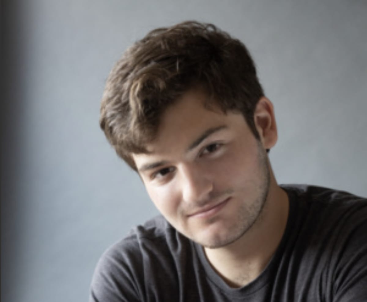 Young journalist Theo Baker holding notepad, representing student accountability journalism at Stanford University