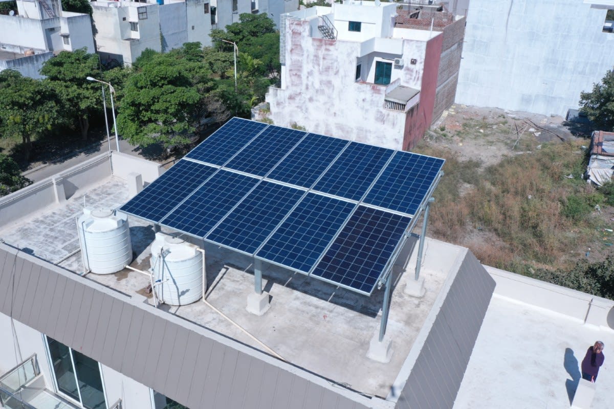 Solar panels installed on residential rooftop in urban Indian neighborhood with clear blue sky