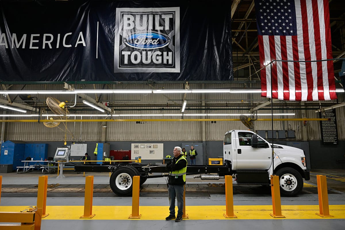 Ford engineers working together in automotive manufacturing facility reviewing vehicle quality standards