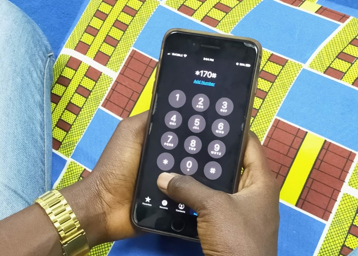 Person using mobile phone to access USSD banking services in Kenya