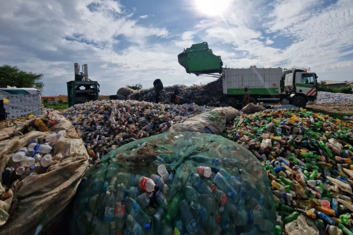 Ecobarter waste collector in Nigeria weighing plastic bottles on a scale during scheduled pickup