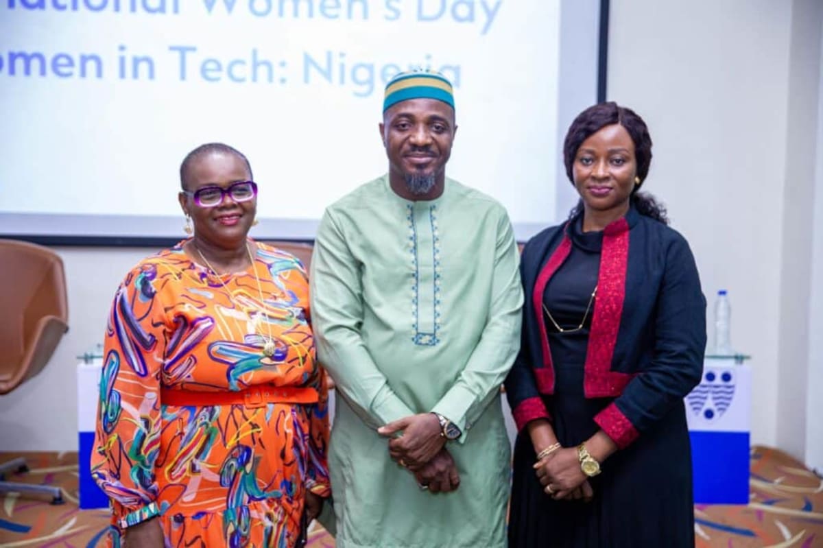 Nigerian women entrepreneurs collaborating on laptops in modern tech workspace, celebrating innovation