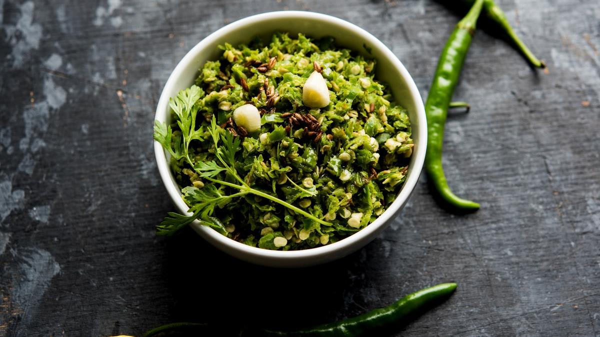 Green chilli thecha condiment with roasted peanuts and garlic in traditional mortar and pestle