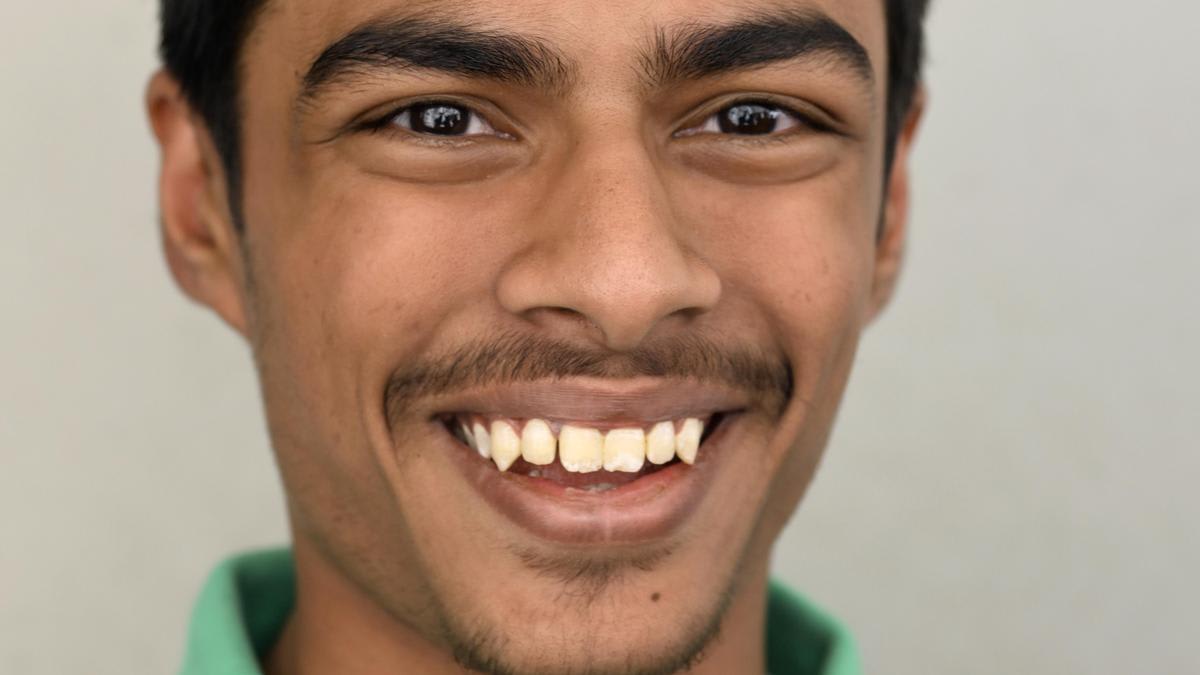 Smiling teenage student in school uniform celebrating academic achievement with teachers
