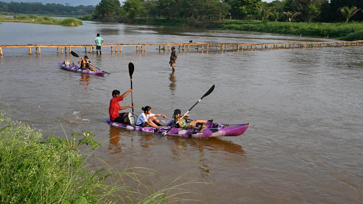Kayakers paddling in tandem on calm Nagavali River waters surrounded by green trees