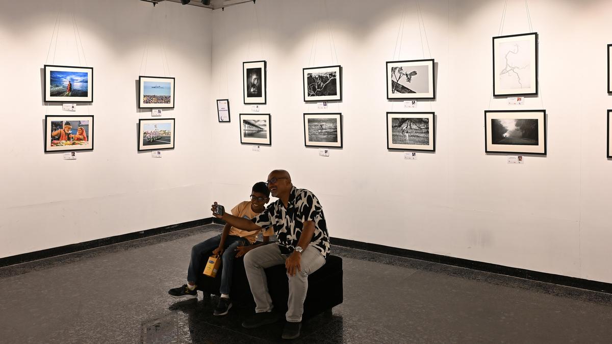 Visitors viewing diverse photographs displayed on white gallery walls at Chennai exhibition