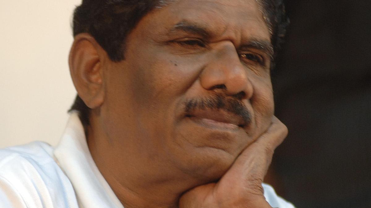 Director Bharathiraja standing with film crew on outdoor village movie set in Tamil Nadu
