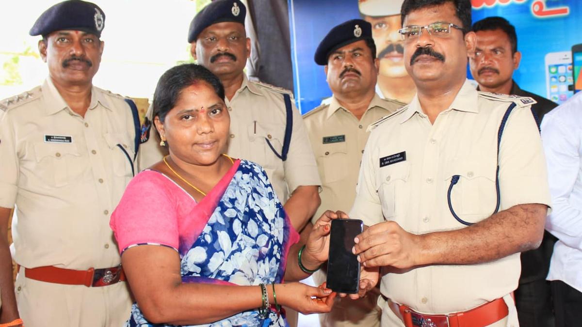 Police officer in India returning recovered mobile phones to grateful owners at ceremony
