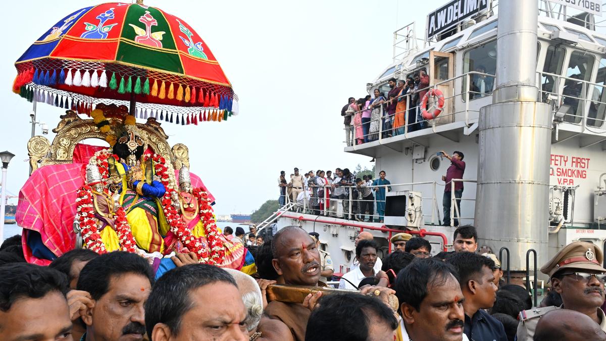 Flower-decorated ceremonial boat carrying Hindu deities through Visakhapatnam port channel with devotees following