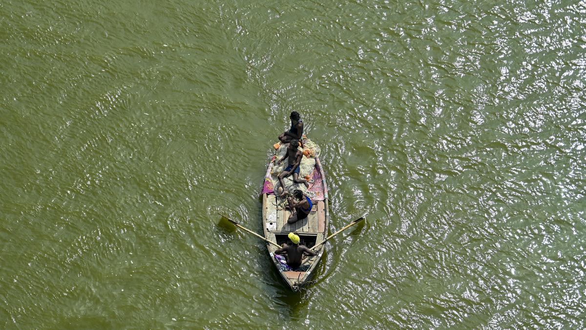 Restored river flowing through rural Indian village with green vegetation along both banks