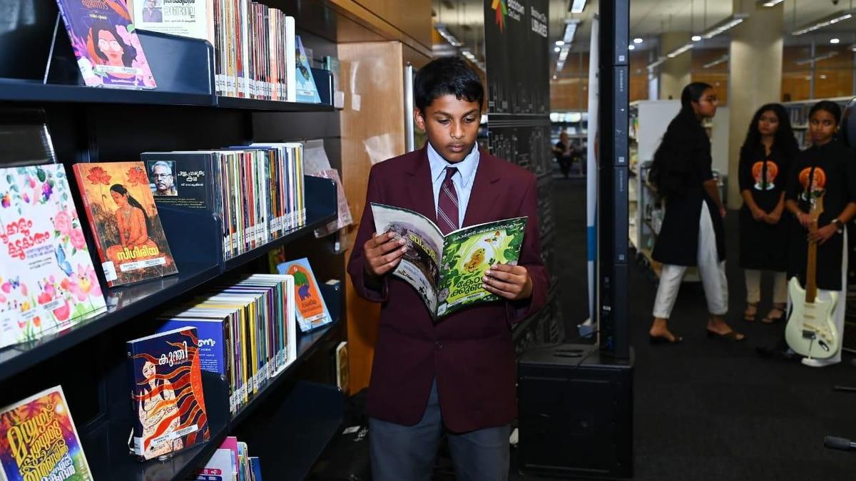 Books on library shelves displaying Malayalam titles in a bright, modern public library space