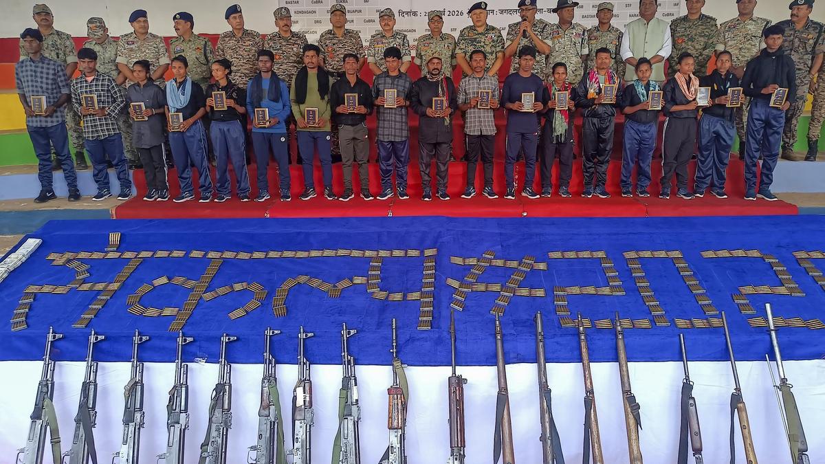 Indian security officials standing with former rebel fighters who surrendered their weapons