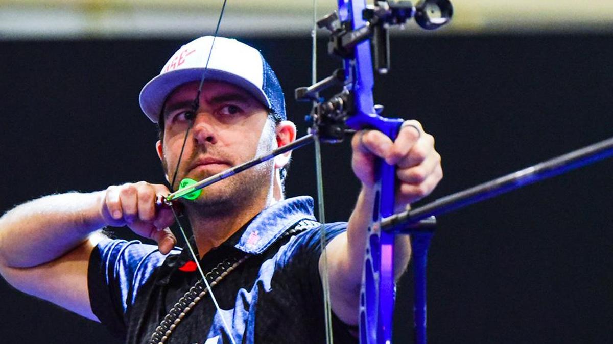 Dave Cousins holding compound bow during competition as world champion archer