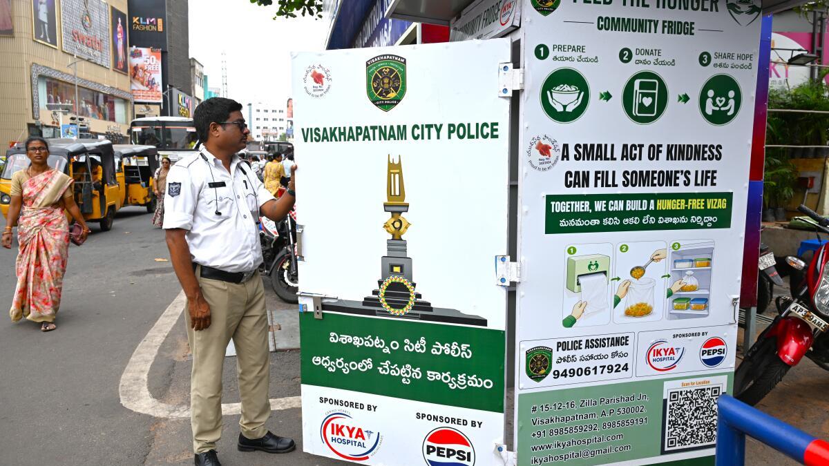 Police officer opening white community refrigerator installed on street in Visakhapatnam India