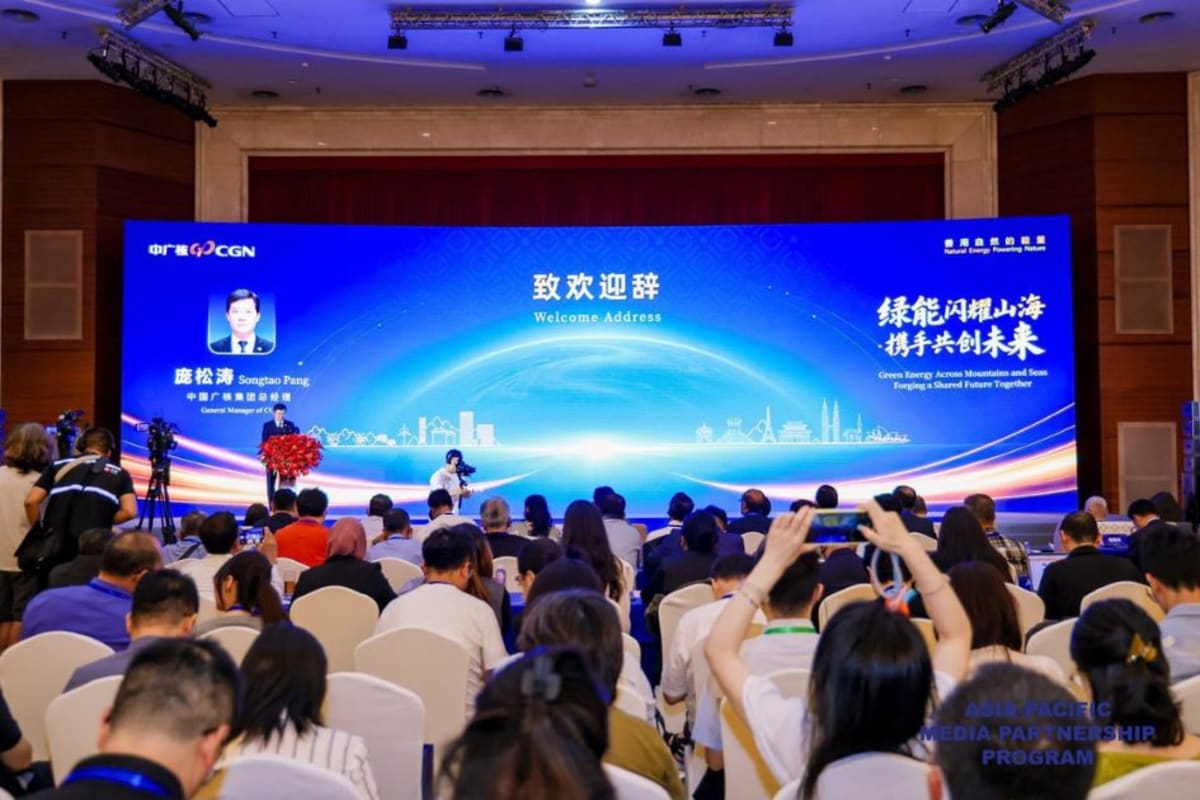 Conference attendees viewing displays of international clean energy projects spanning multiple continents