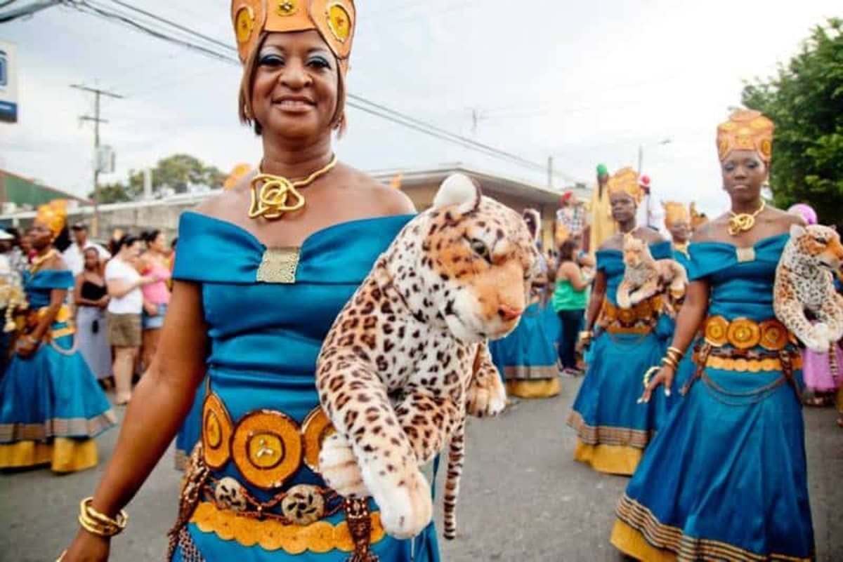 Colorful parade participants in traditional Caribbean costumes dancing through Puerto Viejo streets