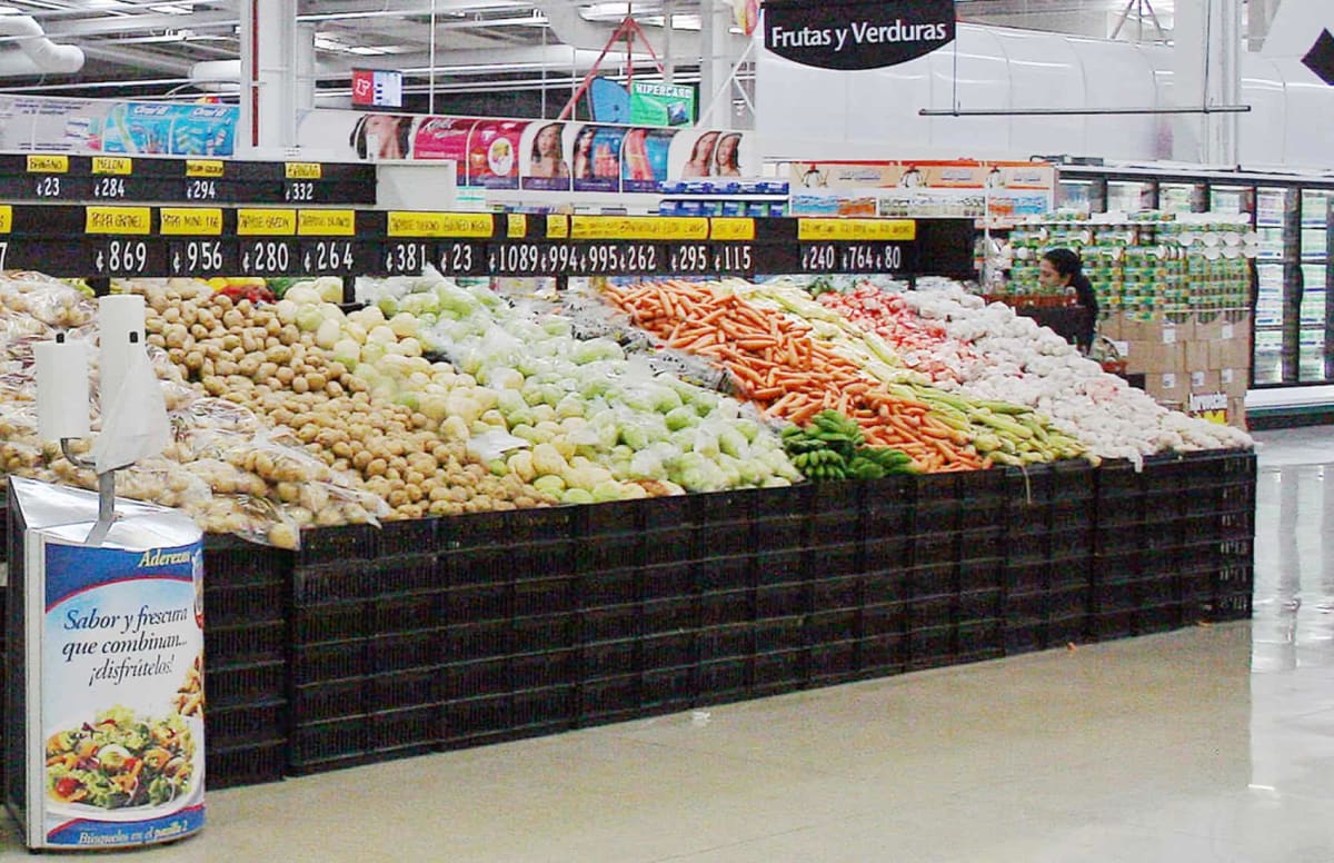 Shoppers selecting fresh produce at a Costa Rican market with affordable price tags displayed