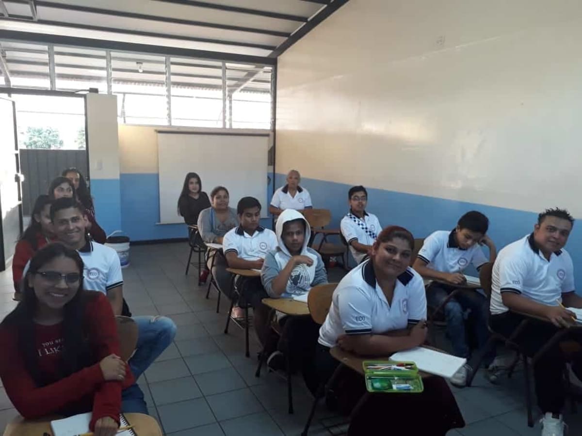 Costa Rican students in rural classroom learning English through interactive video lesson on digital screens