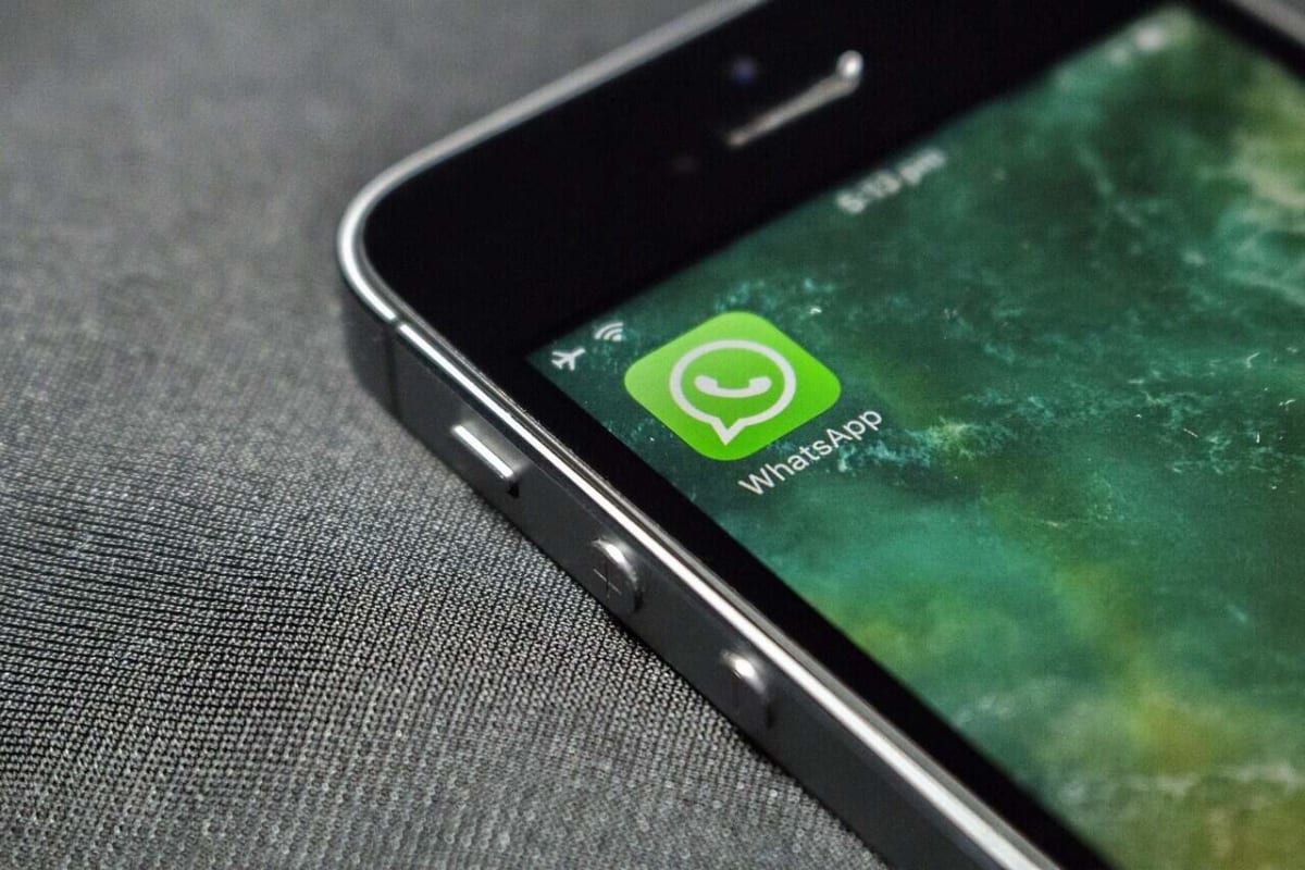 Traveler using smartphone to message WhatsApp help line at modern airport terminal