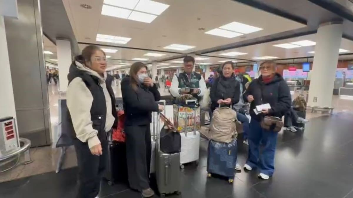 Filipino workers boarding transportation with luggage, assisted by government support staff in Barcelona