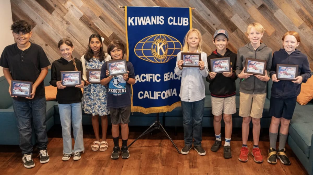 ** Eight elementary students holding award plaques and smiling at Pacific Beach ceremony