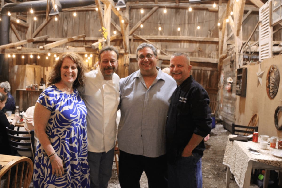 Cancer survivors and medical staff gathered together at elegant farm dinner celebrating survivorship