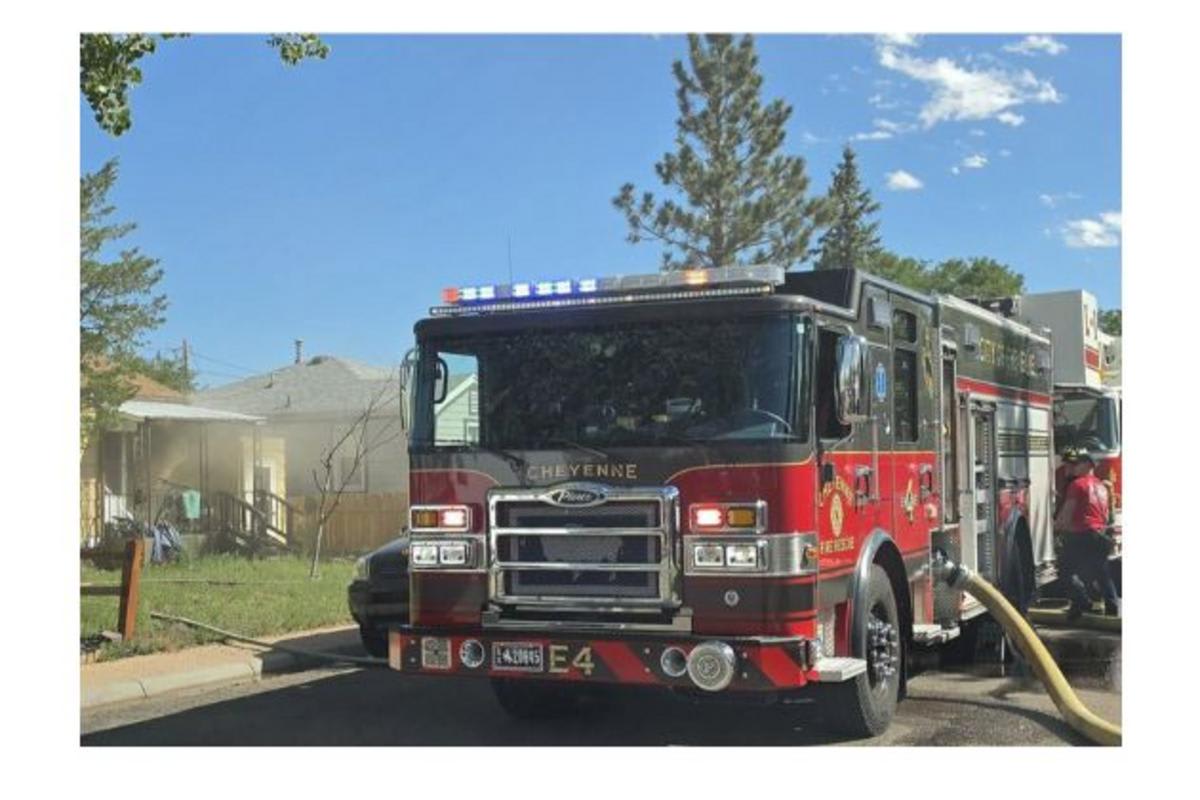 Cheyenne firefighter in full gear holding rescued cat after basement fire rescue