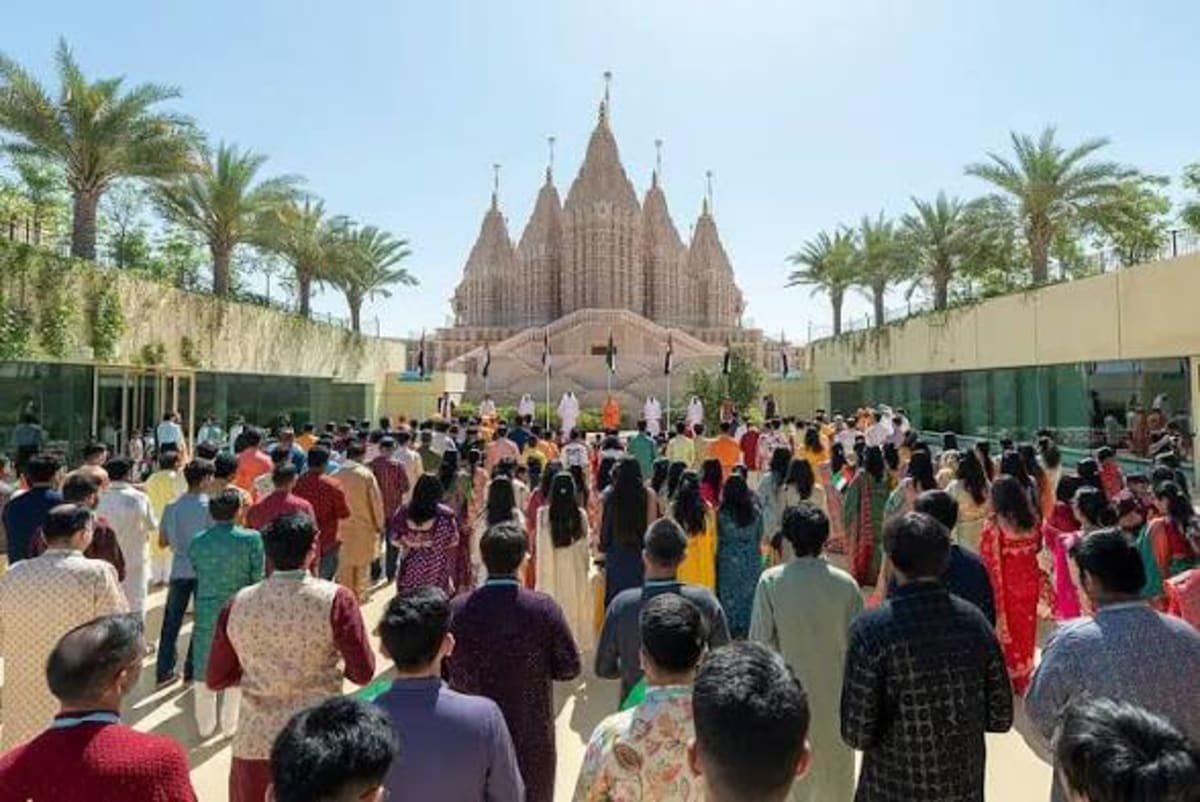 Diverse crowd waving UAE flags during unity celebration at BAPS Hindu Mandir Abu Dhabi